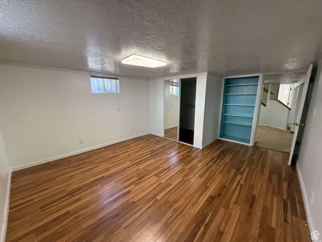 Below grade area with a textured ceiling, dark wood-type flooring, and built in features
