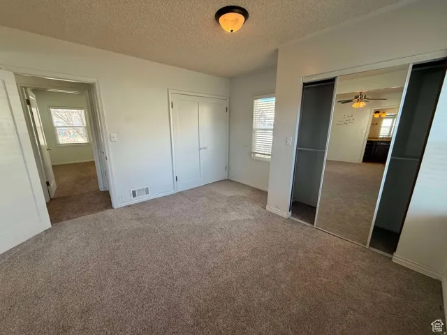 Unfurnished bedroom featuring carpet floors, a textured ceiling, and two closets