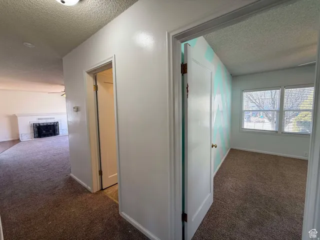 Corridor featuring dark carpet and a textured ceiling