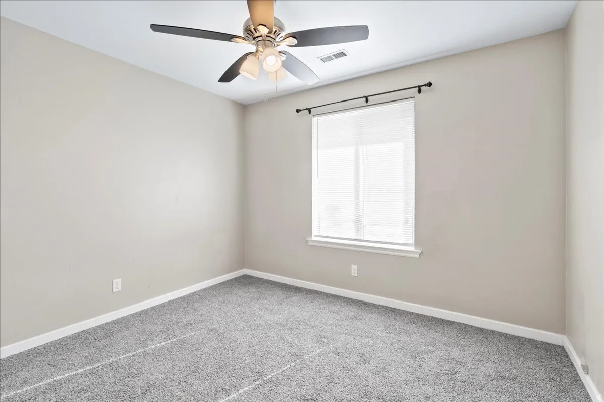 Carpeted empty room featuring baseboards and a ceiling fan