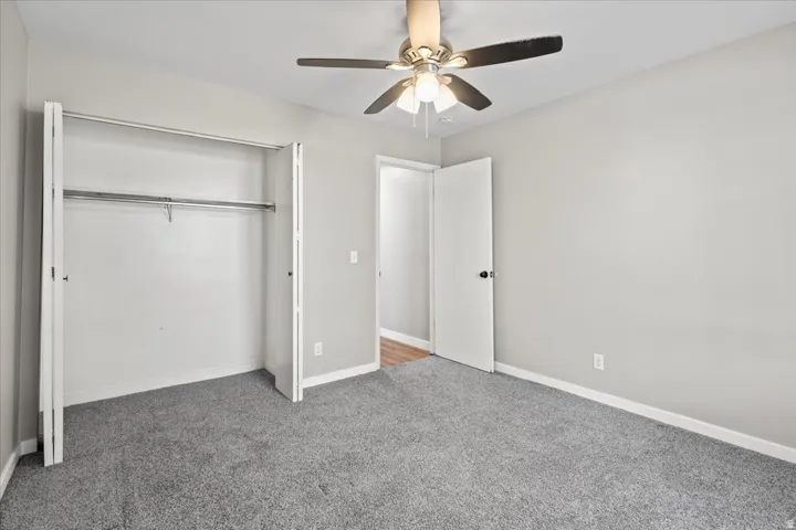 Unfurnished bedroom with carpet floors, a closet, and a ceiling fan