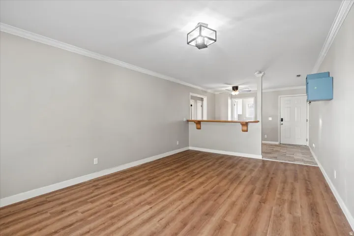 Living room featuring crown molding, wood finished floors, and ceiling fan