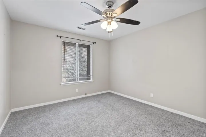 Carpeted empty room with baseboards and a ceiling fan
