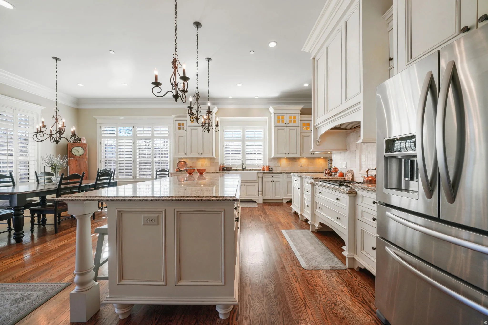 Kitchen with stainless steel appliances, glass fronted cabinets, light stone counters, ornamental molding, and a kitchen island