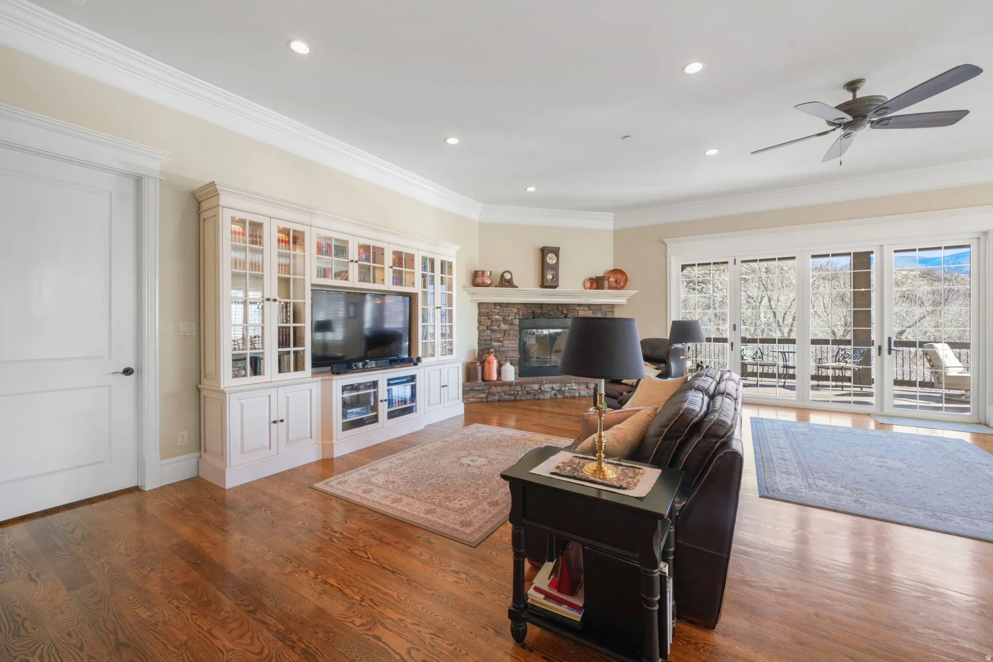Living area featuring ornamental molding, ceiling fan, wood finished floors, a stone fireplace, and recessed lighting