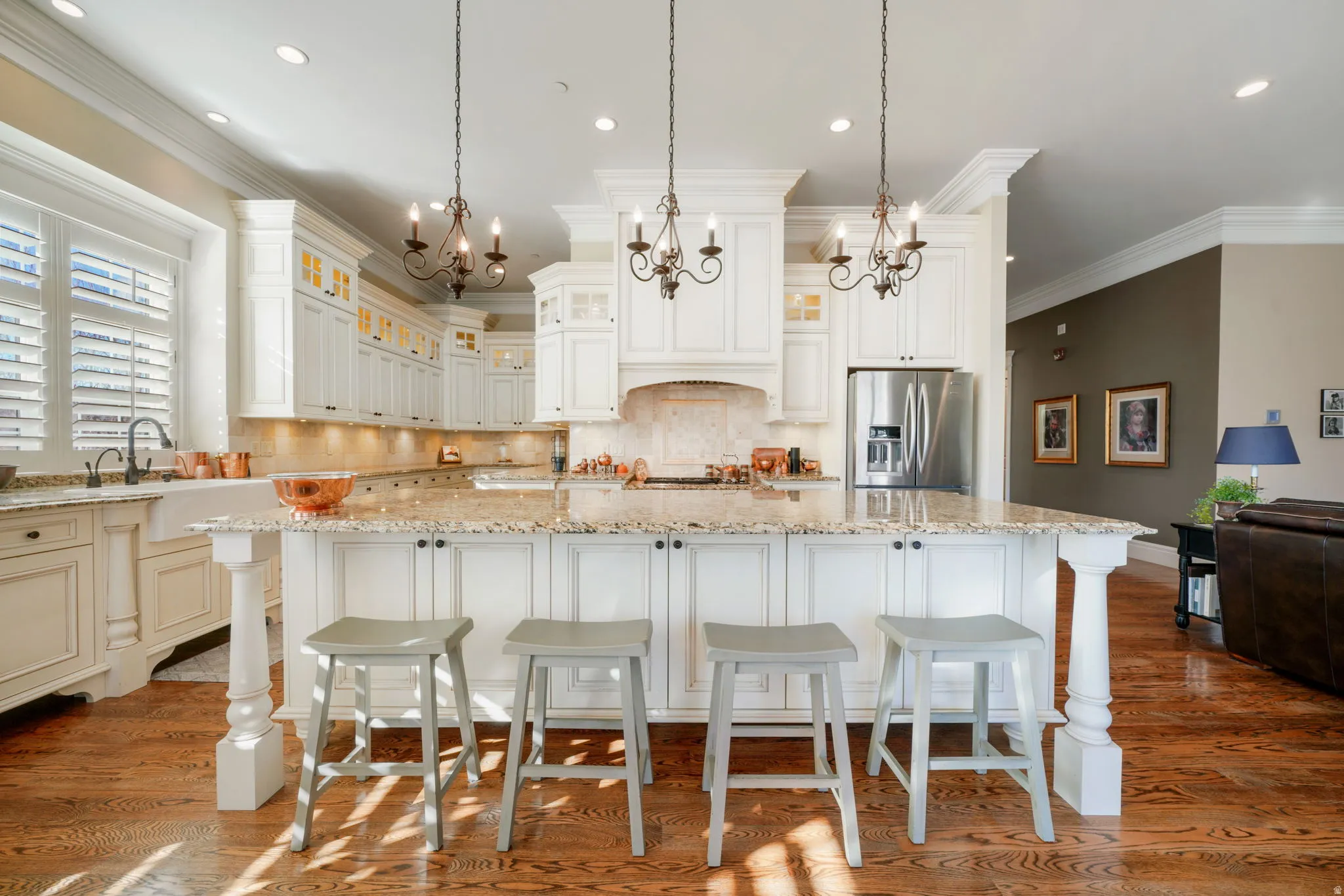 Kitchen featuring backsplash, light stone countertops, a spacious island, ornamental molding, and suspended lighting
