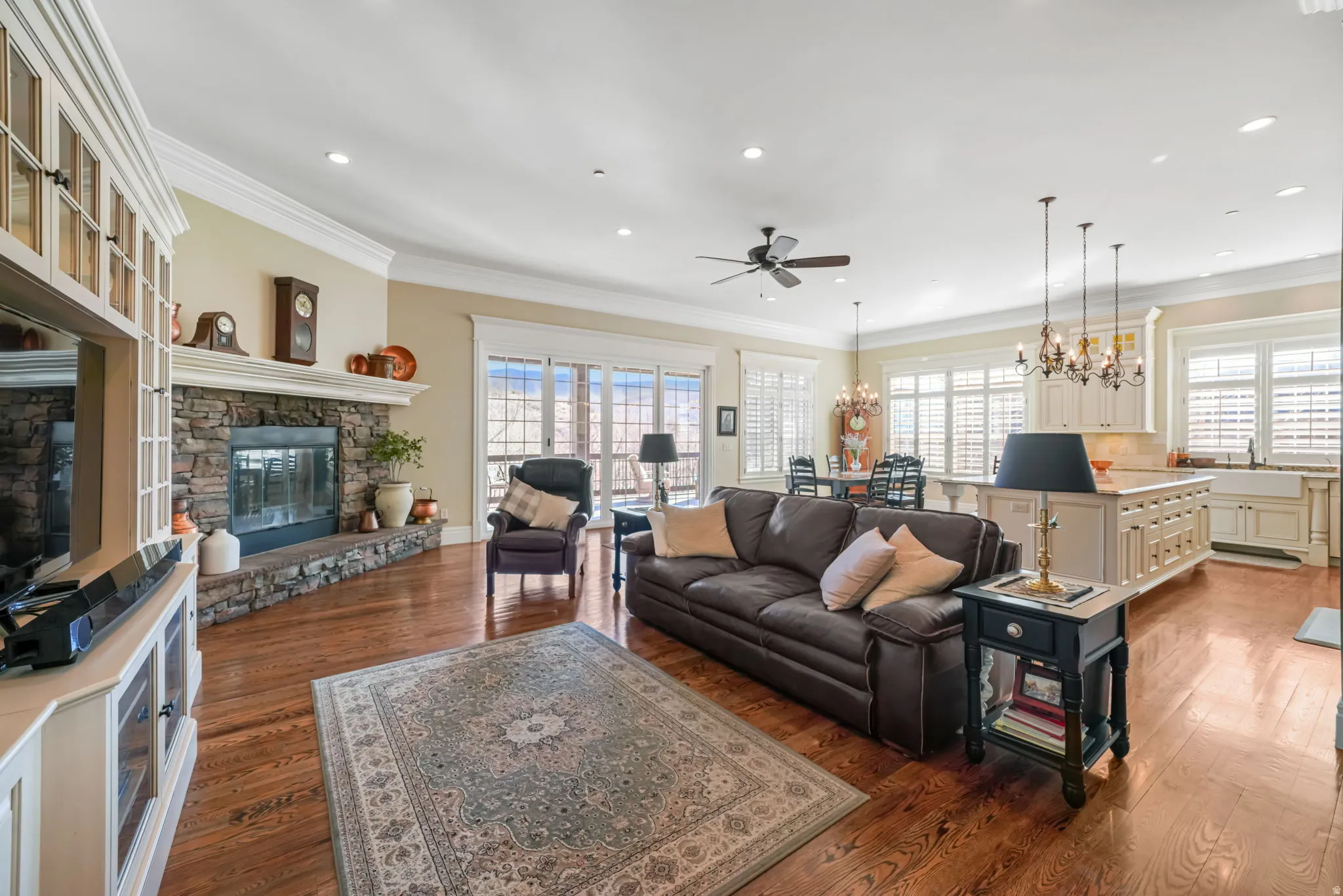 Living area featuring crown molding, hardwood / wood-style floors, ceiling fan, a chandelier, and plenty of natural light