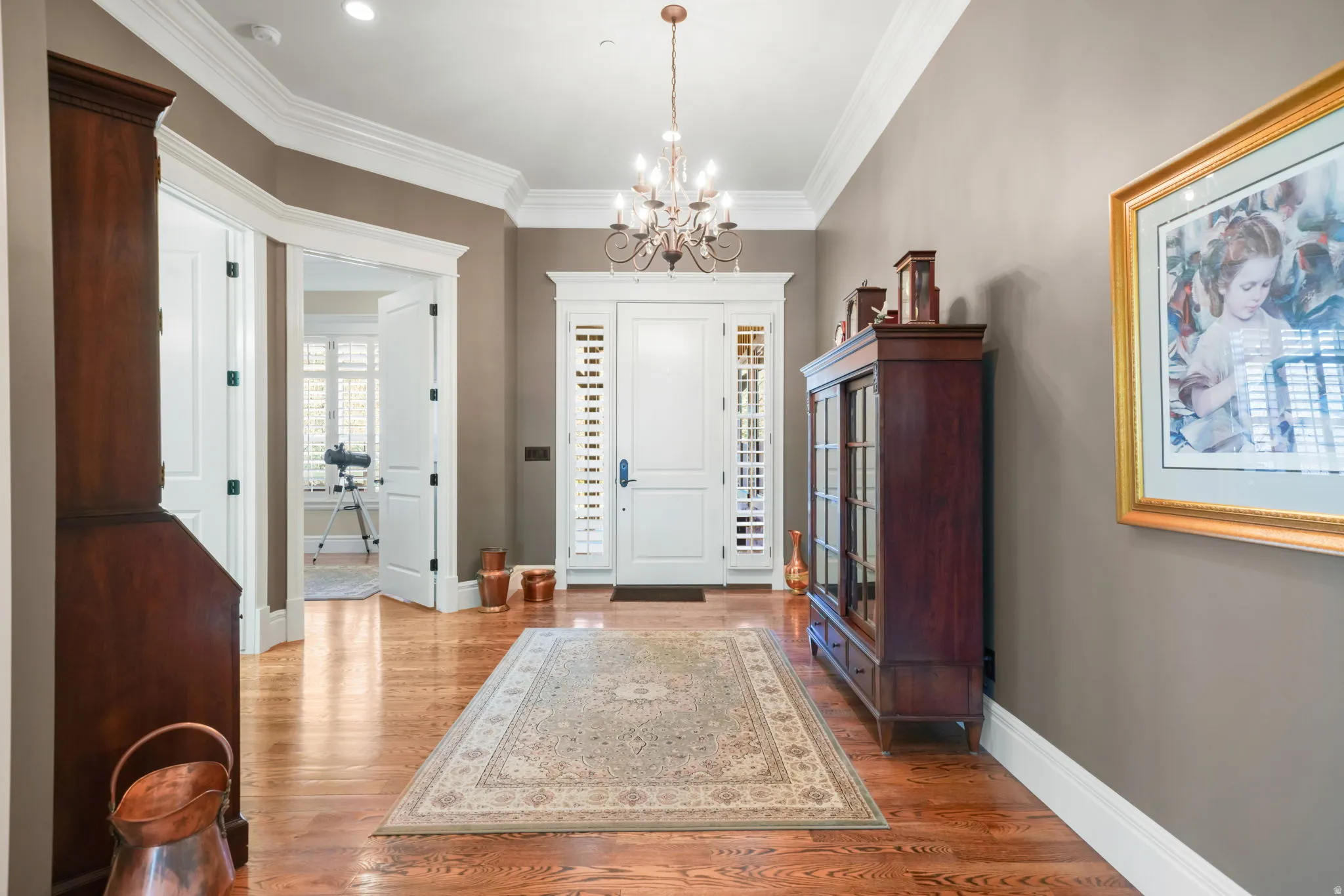 Entrance foyer with ornamental molding, hanging lights, and light wood-style floors