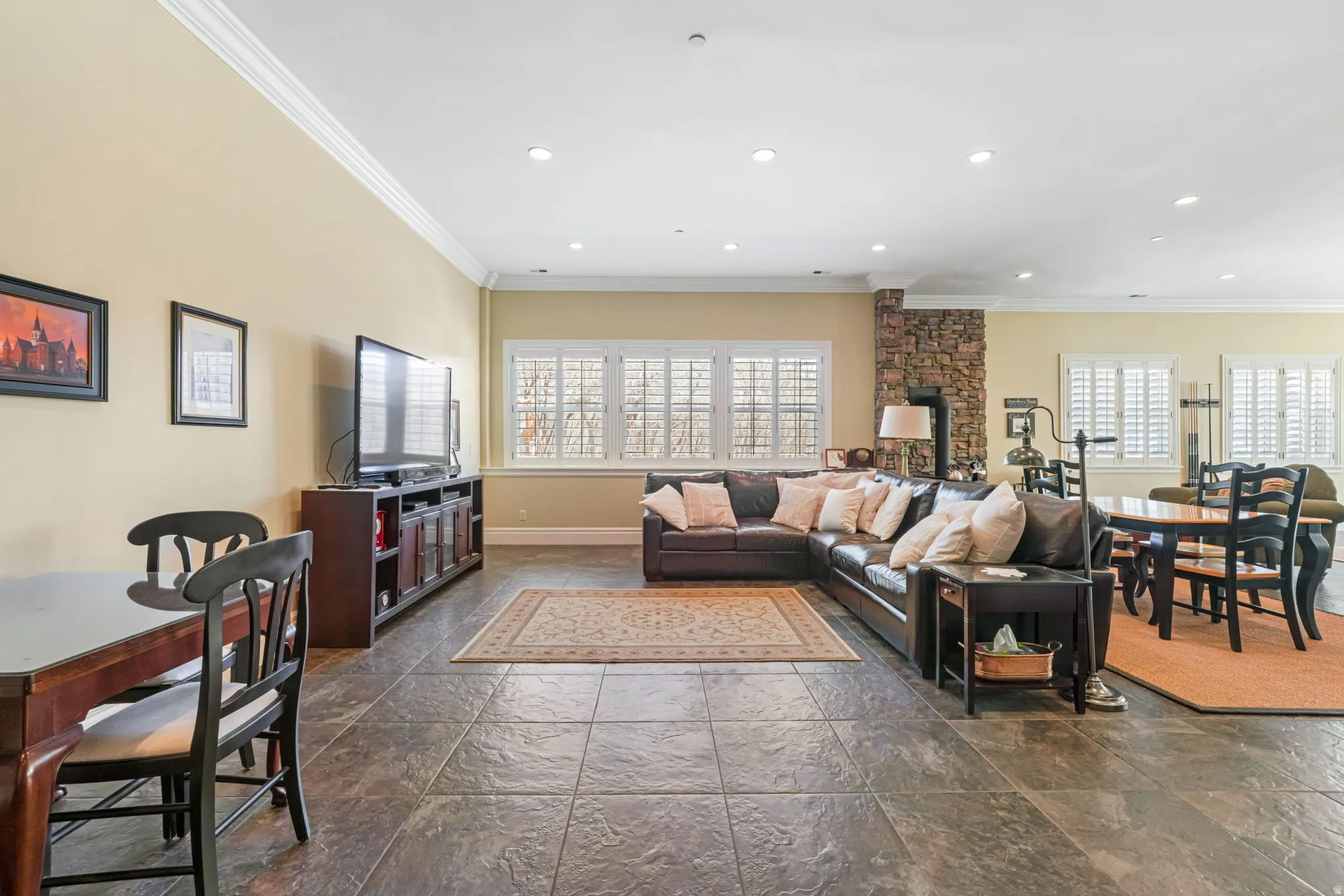 Living room with stone tile floors, ornamental molding, and recessed lighting