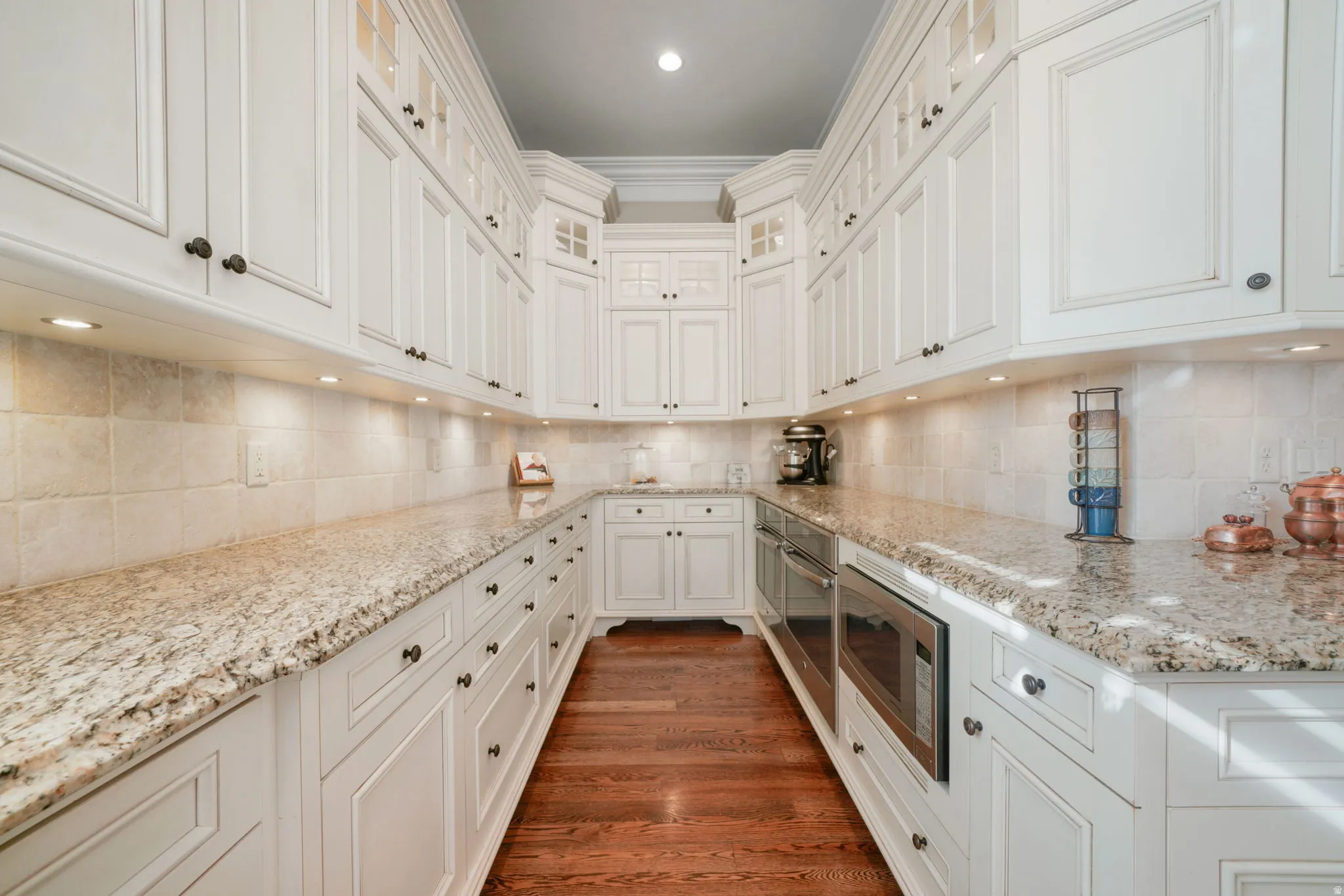 Kitchen featuring glass insert cabinets, white cabinets, stainless steel appliances, recessed lighting, and dark wood-type flooring