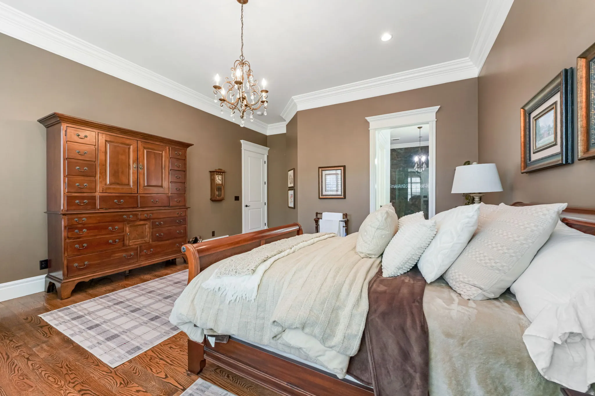 Bedroom with suspended lighting, crown molding, and wood finished floors