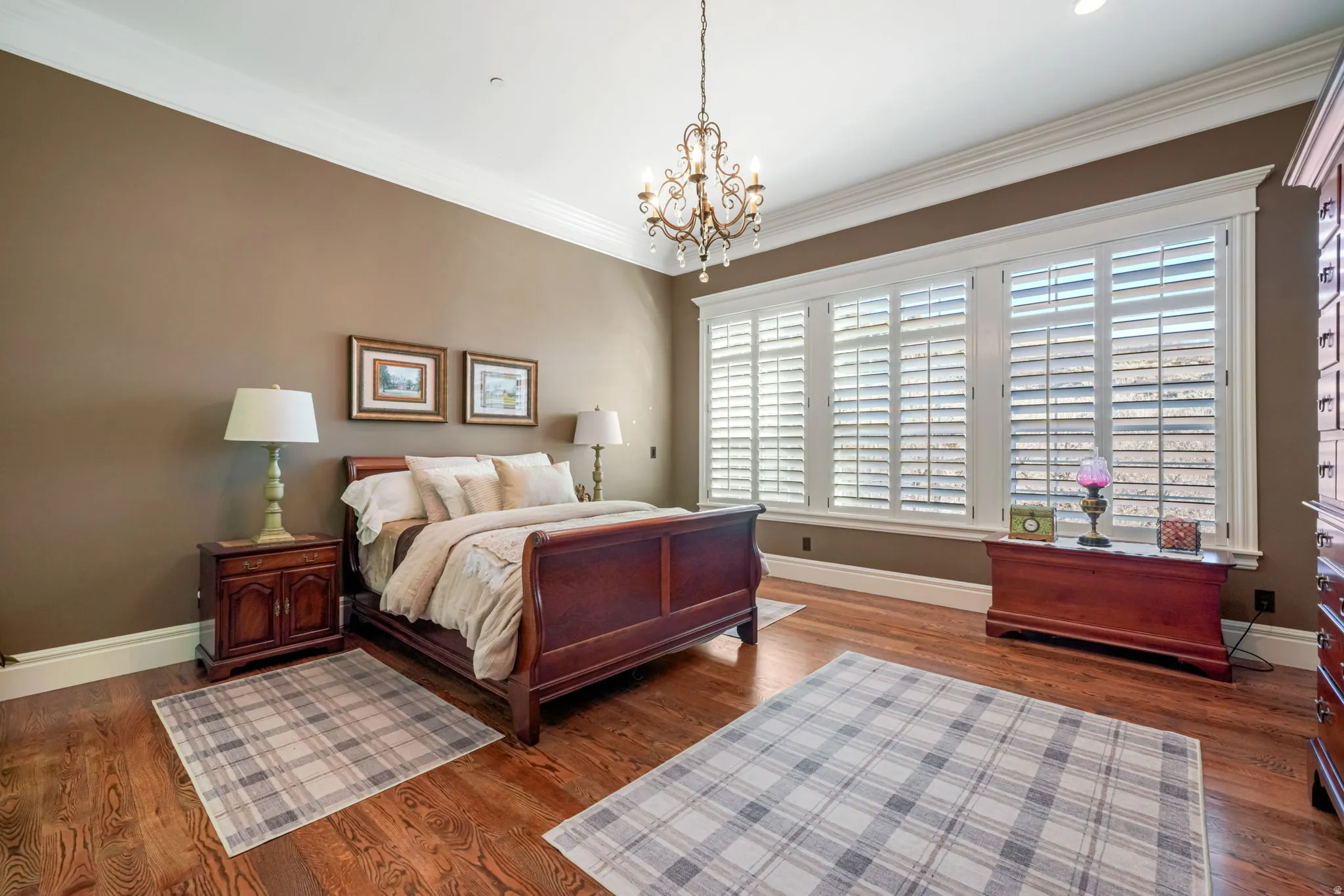 Bedroom with dark wood finished floors, hanging lights, and crown molding