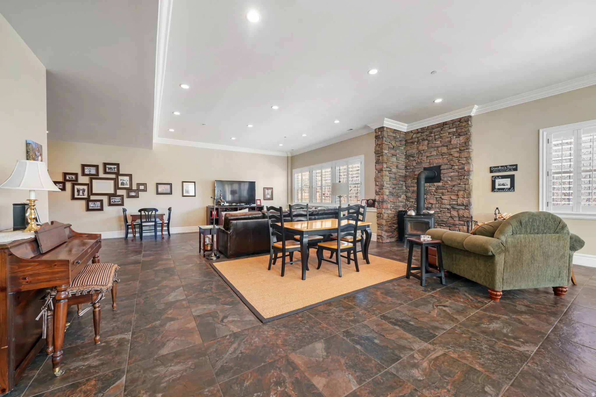 Dining area featuring a wood stove, ornamental molding, recessed lighting, and dark stone finish floors