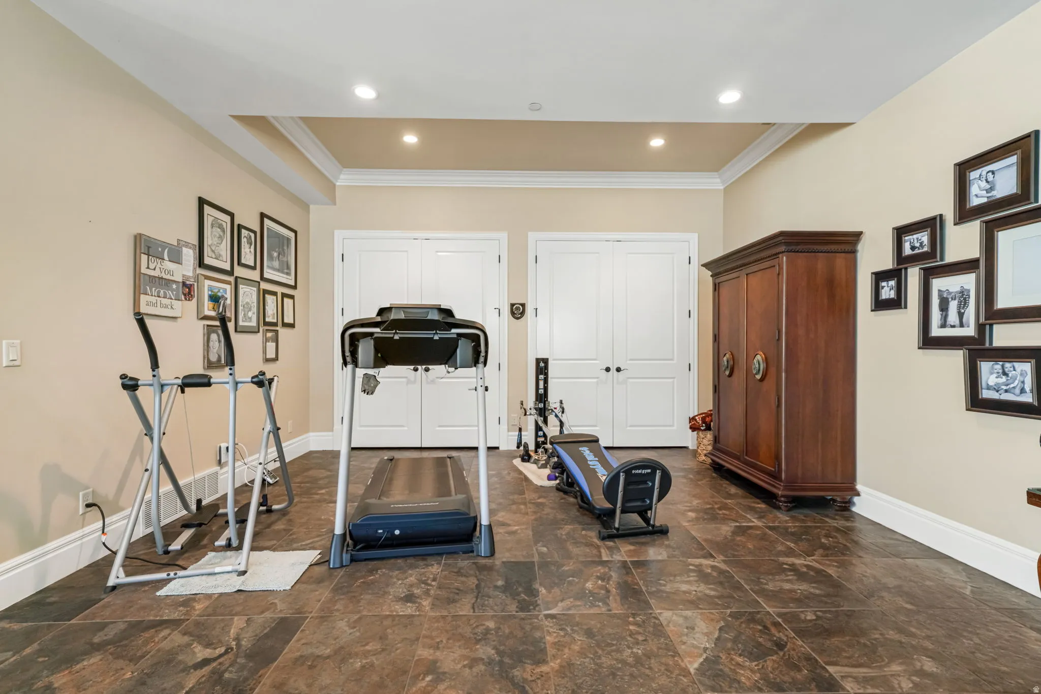 Workout room featuring ornamental molding and dark stone finish floors