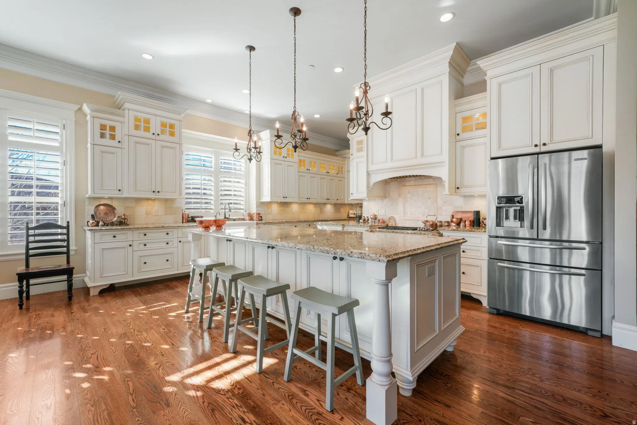 Kitchen with stainless steel fridge with ice dispenser, glass insert cabinets, light stone countertops, decorative backsplash, and crown molding