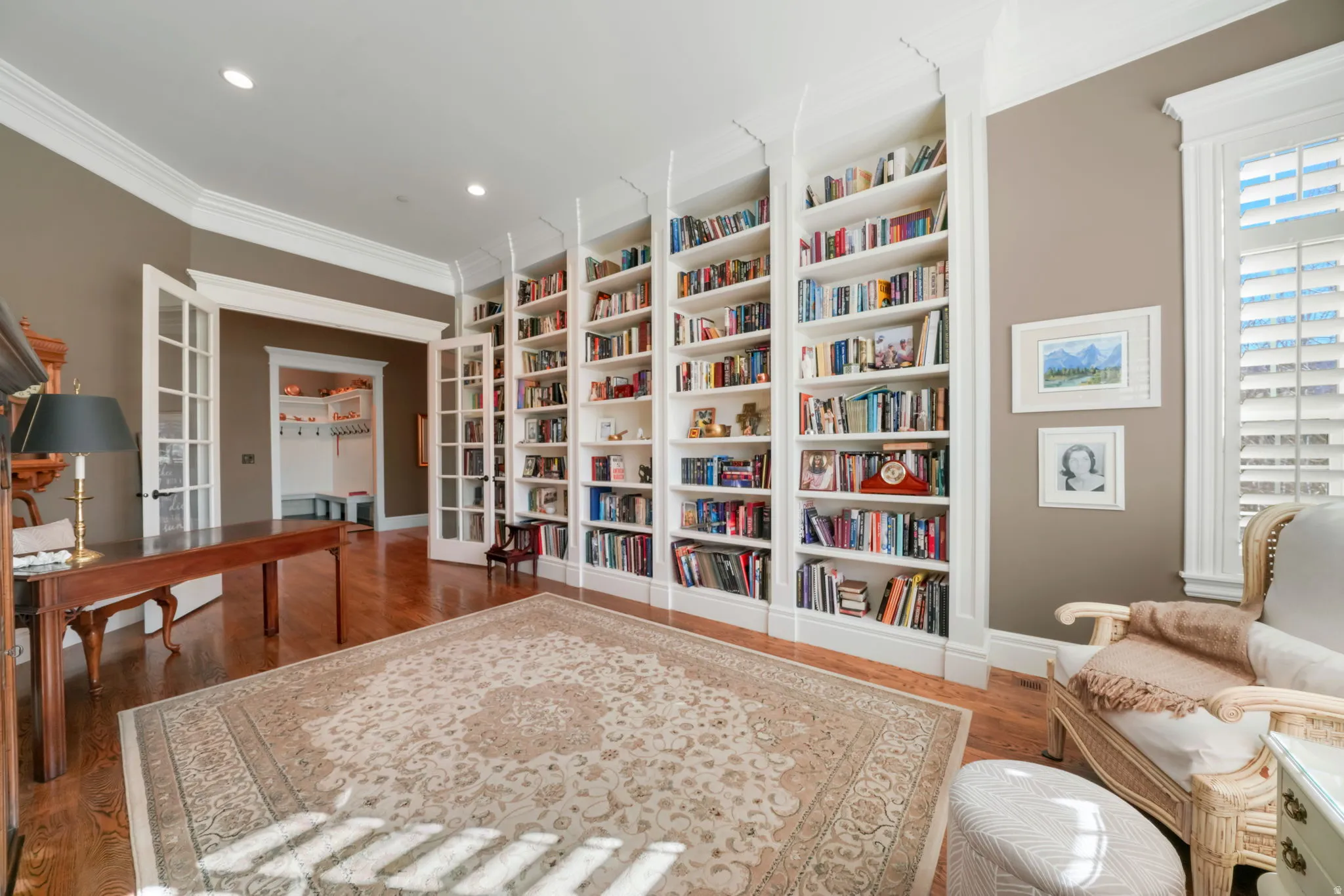 Living area featuring dark wood-style flooring, crown molding, built in shelves, bookshelves, and recessed lighting