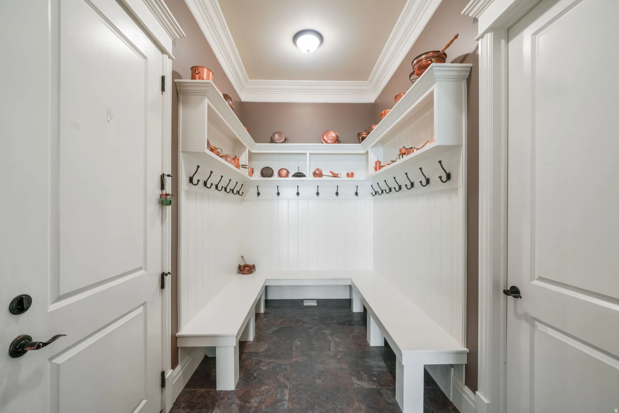 Mudroom featuring crown molding and dark stone finish floors