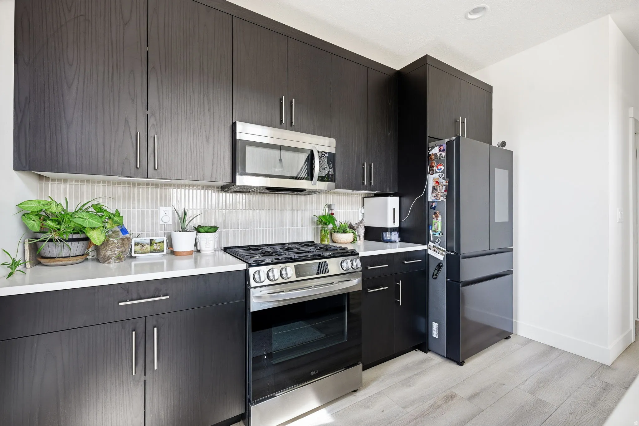 Kitchen with stainless steel appliances, decorative backsplash, light wood finished floors, and modern cabinets