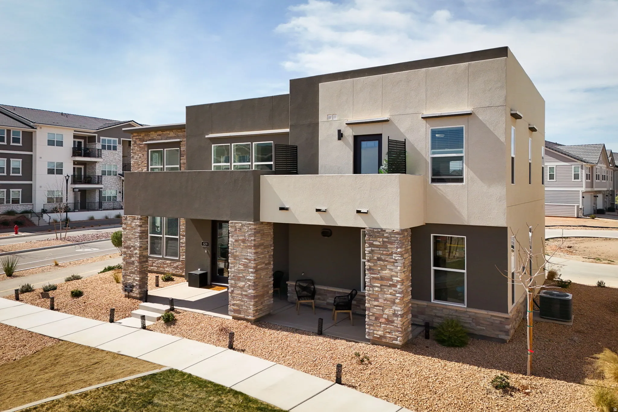 Contemporary house featuring stucco siding, stone siding, and covered porch