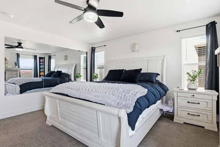 Bedroom featuring a ceiling fan and dark colored carpet