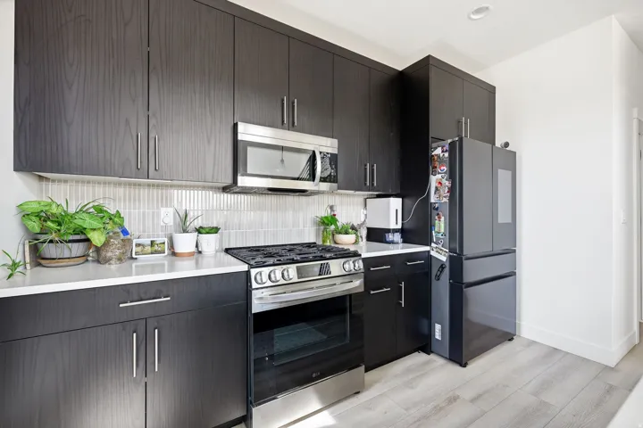 Kitchen with stainless steel appliances, decorative backsplash, light wood finished floors, and modern cabinets