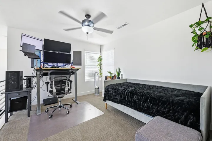 Bedroom with a desk, carpet, and a ceiling fan
