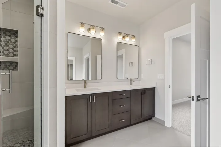 Full bathroom with double vanity, a stall shower, and light tile patterned floors