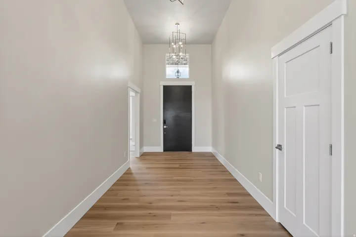 Foyer entrance featuring a chandelier, light wood-style flooring, and a high ceiling
