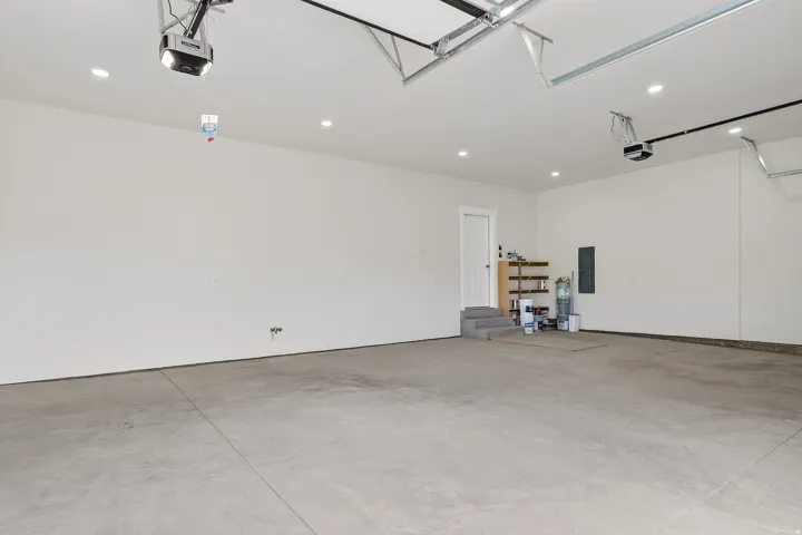 Garage with recessed lighting, electric panel, and a garage door opener