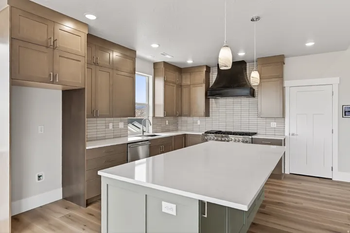 Dual tone kitchen featuring two tone cabinets, a center island, hanging light fixtures, light wood-style flooring, and tasteful backsplash