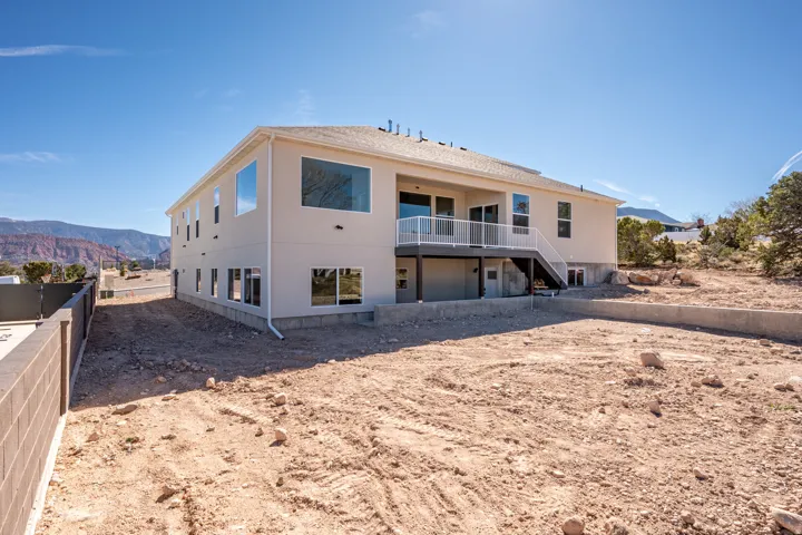 Rear view of property featuring a garage, a deck with mountain view, and stucco siding