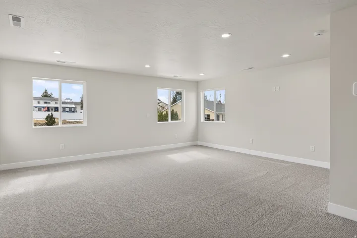 Empty room with light carpet, healthy amount of natural light, recessed lighting, and a textured ceiling