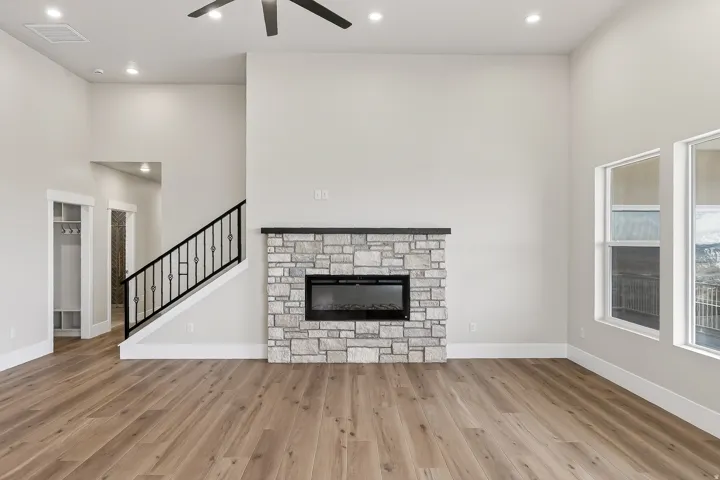 Unfurnished living room with a fireplace, a high ceiling, recessed lighting, light wood finished floors, and a ceiling fan