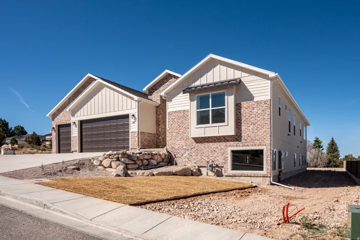 View of front of home with board and batten siding, a garage, concrete driveway, and brick siding
