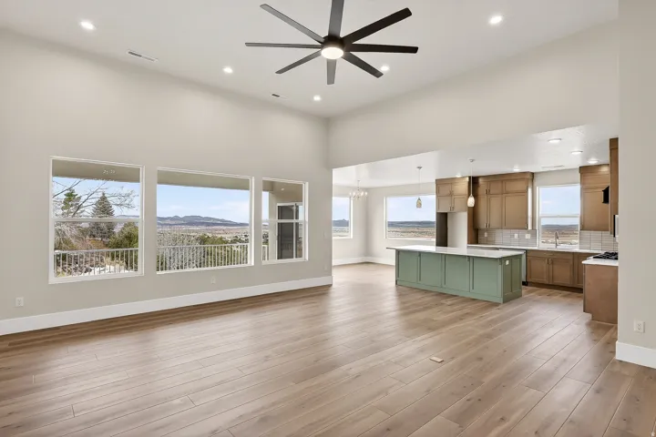 Unfurnished living room featuring a ceiling fan, a mountain view, suspended lighting, a high ceiling, and light wood-type flooring
