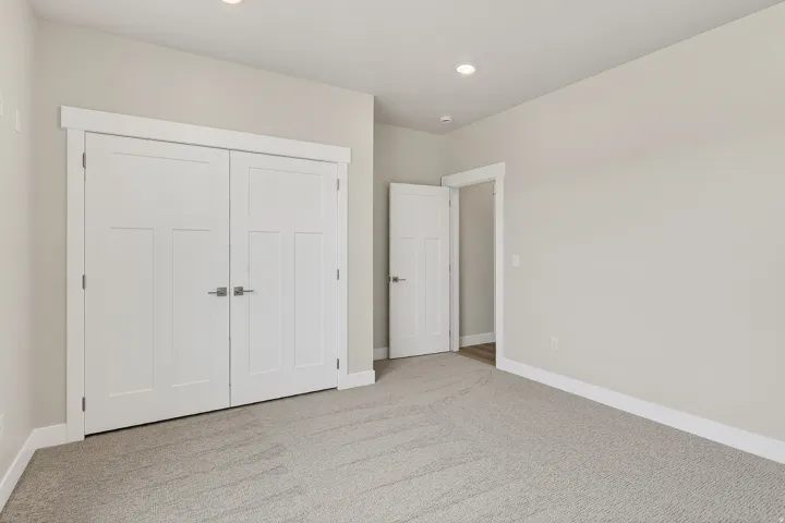 Unfurnished bedroom with light colored carpet, a closet, and recessed lighting
