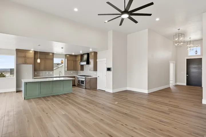 Kitchen featuring open floor plan, ceiling fan, tasteful backsplash, a center island, and range with two ovens