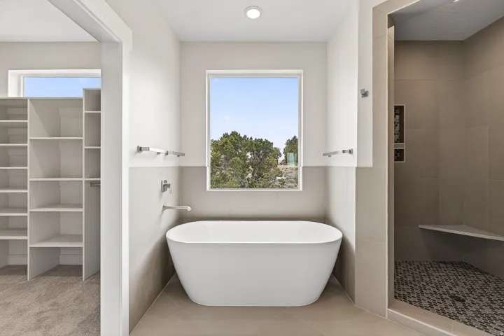 Bathroom with a freestanding tub, a tile shower, tile walls, and light tile patterned floors