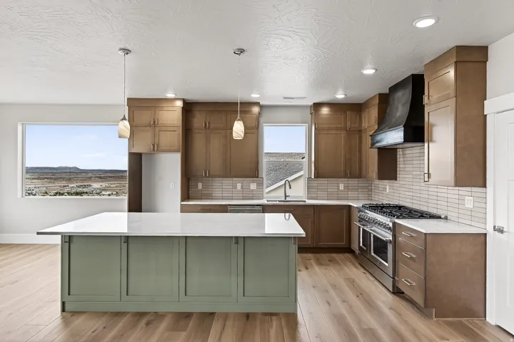 Kitchen featuring double oven range, light stone counters, a kitchen island, light wood-style floors, and hanging light fixtures