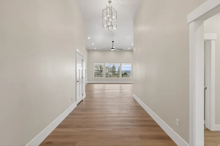 Hall with light wood-type flooring, a high ceiling, and hanging lights