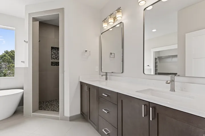 Bathroom featuring light tile patterned floors, a freestanding bath, a walk in shower, double vanity, and a walk in closet