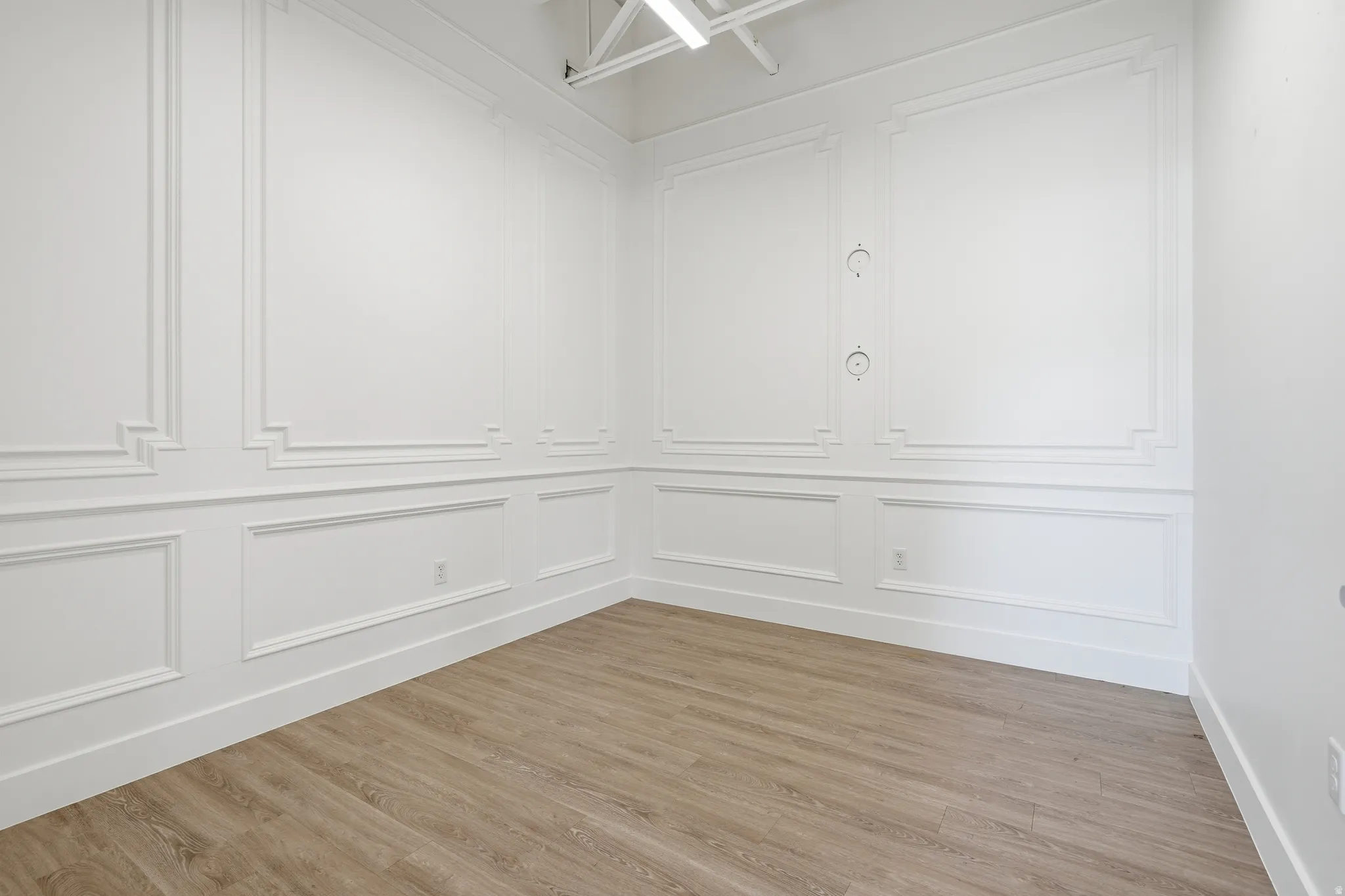 Unfurnished room with light wood-style flooring, a decorative wall, and elevator