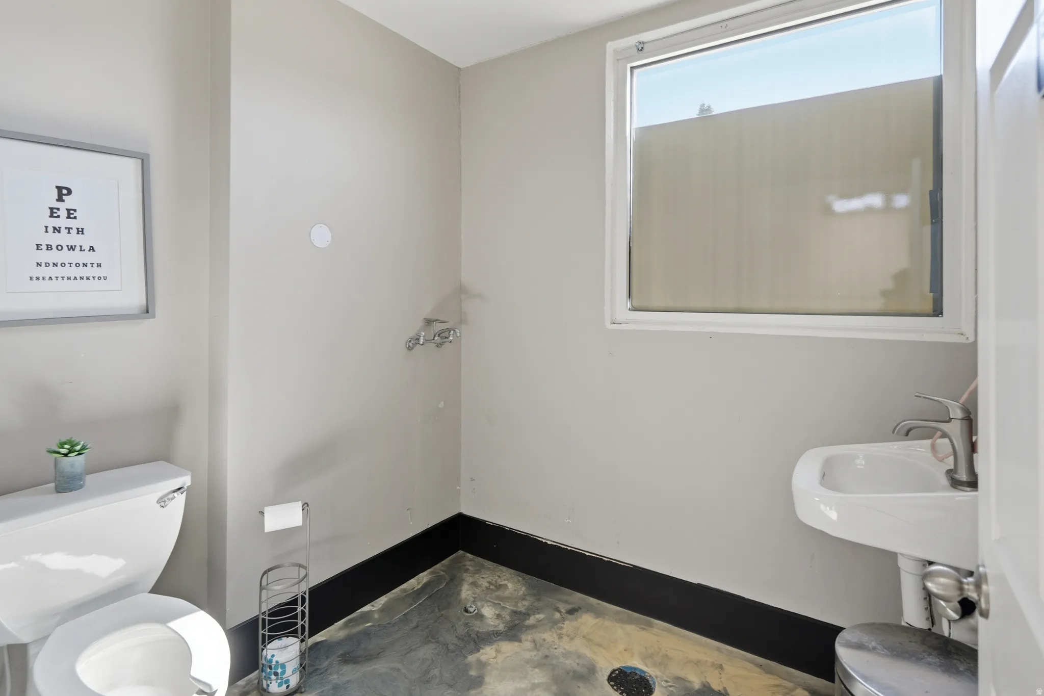 Half bath featuring toilet and unfinished concrete flooring