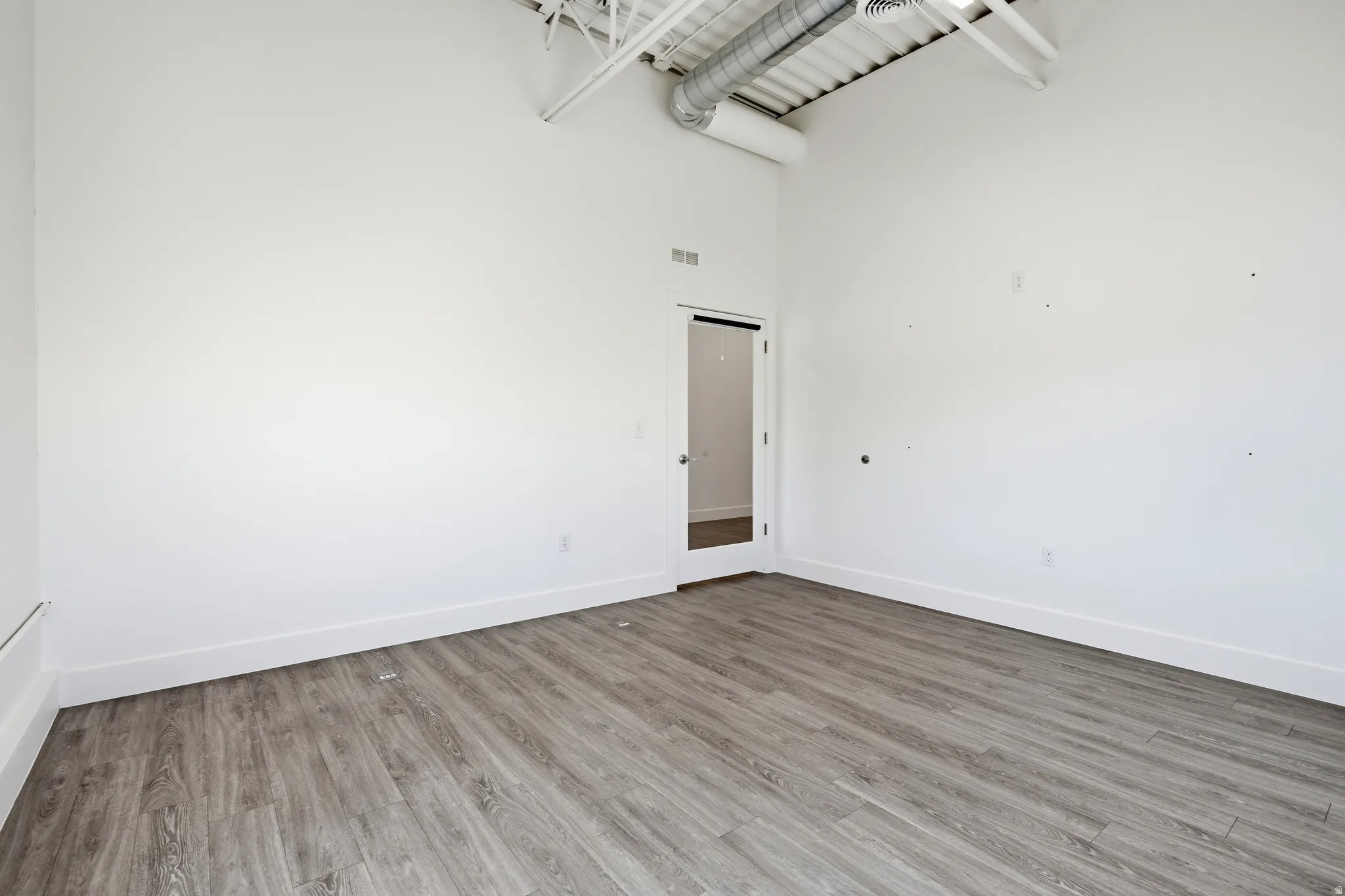 Spare room with light wood-style floors and a high ceiling