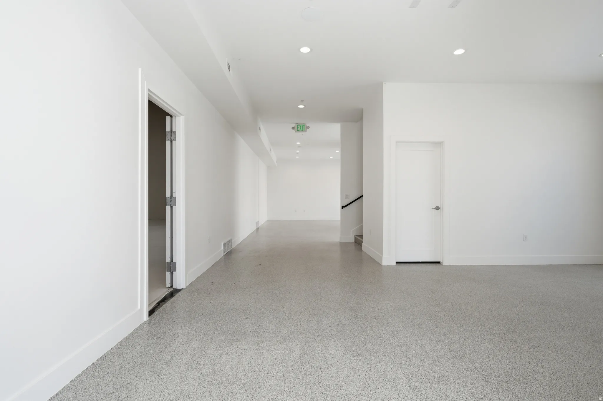 Empty room with epoxy flooring and recessed lighting