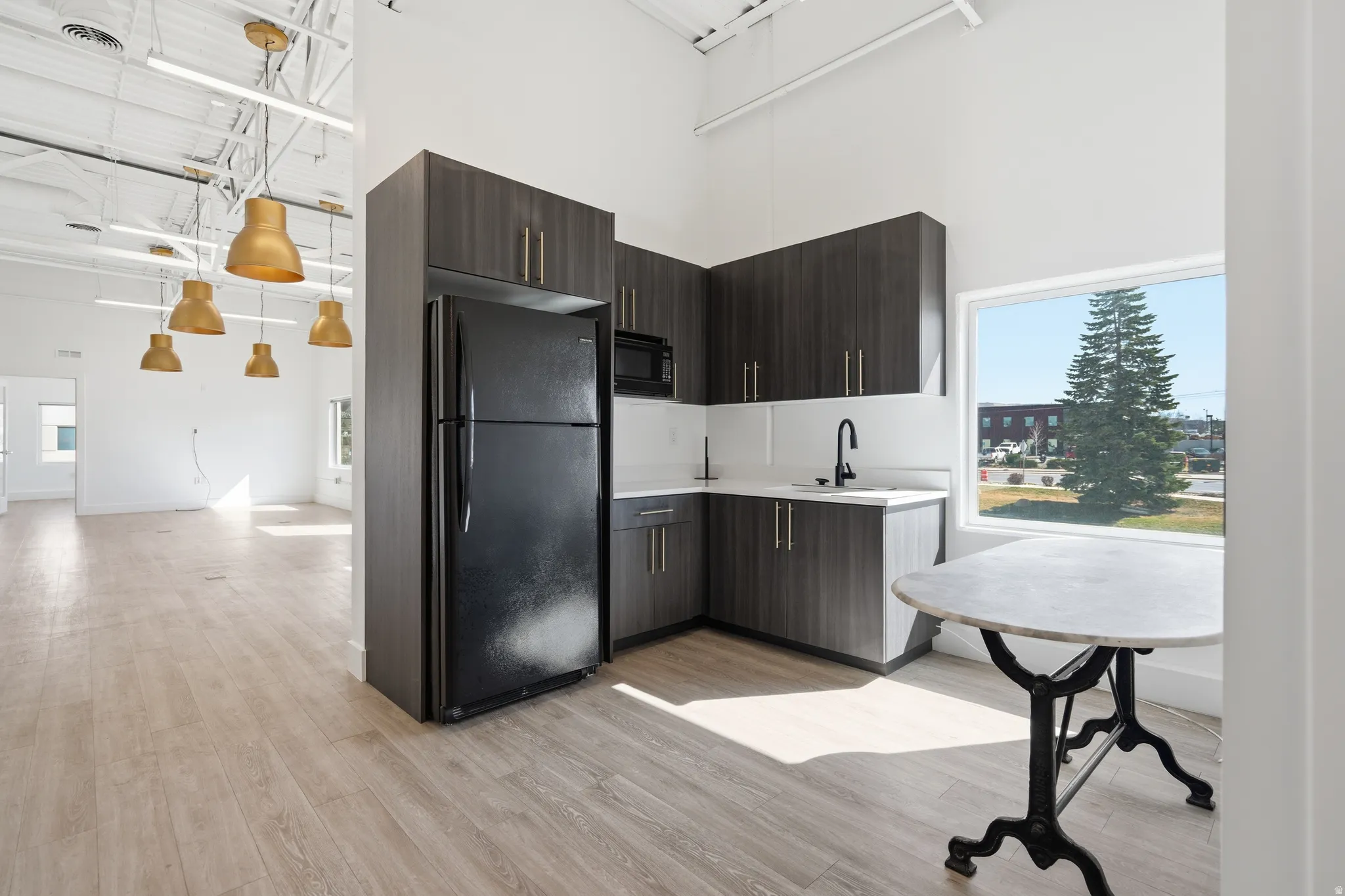 Kitchen featuring black appliances, light countertops, modern cabinets, a high ceiling, and dark wood finish cabinetry