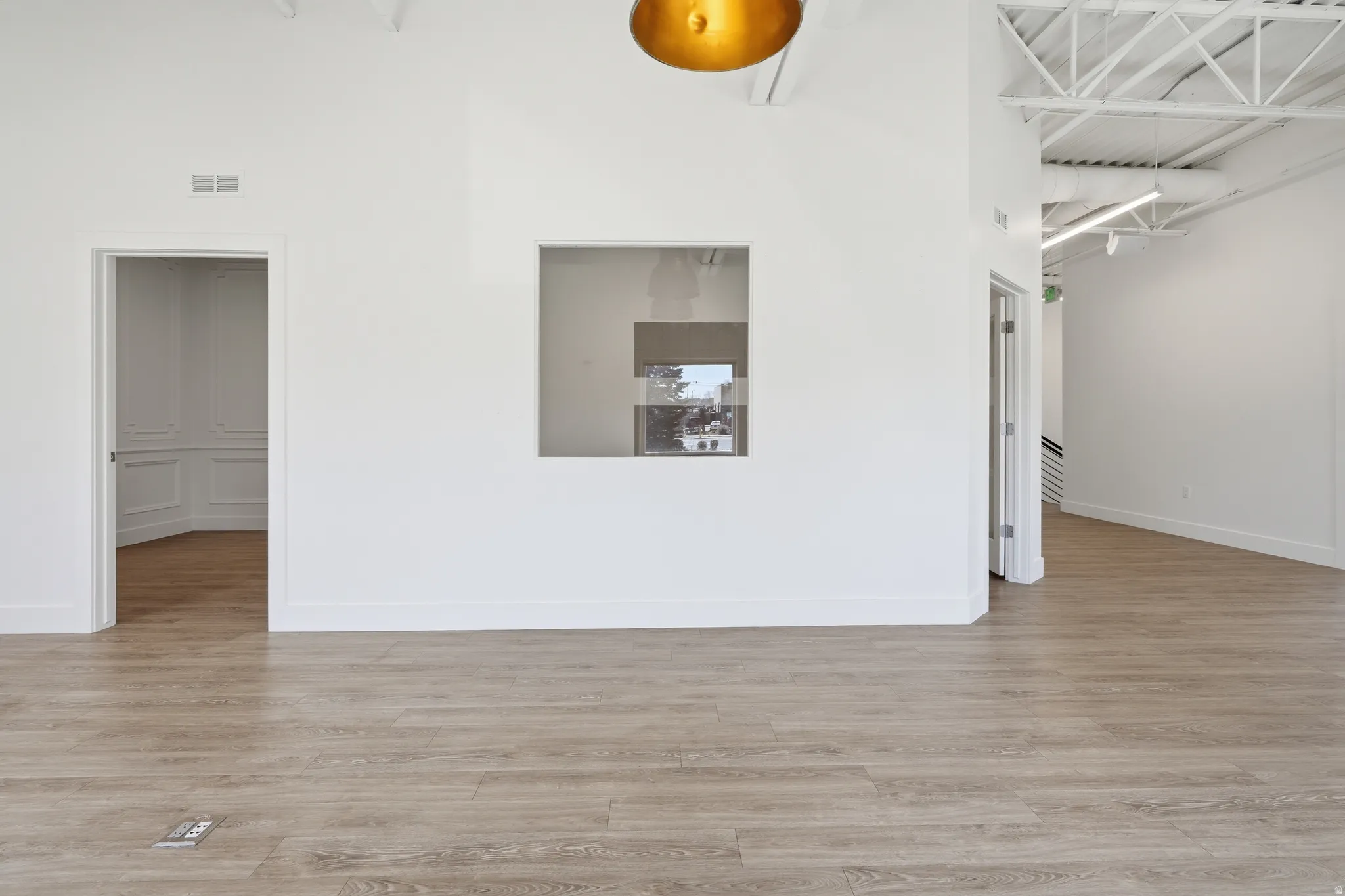 Spare room featuring light wood-type flooring and a high ceiling