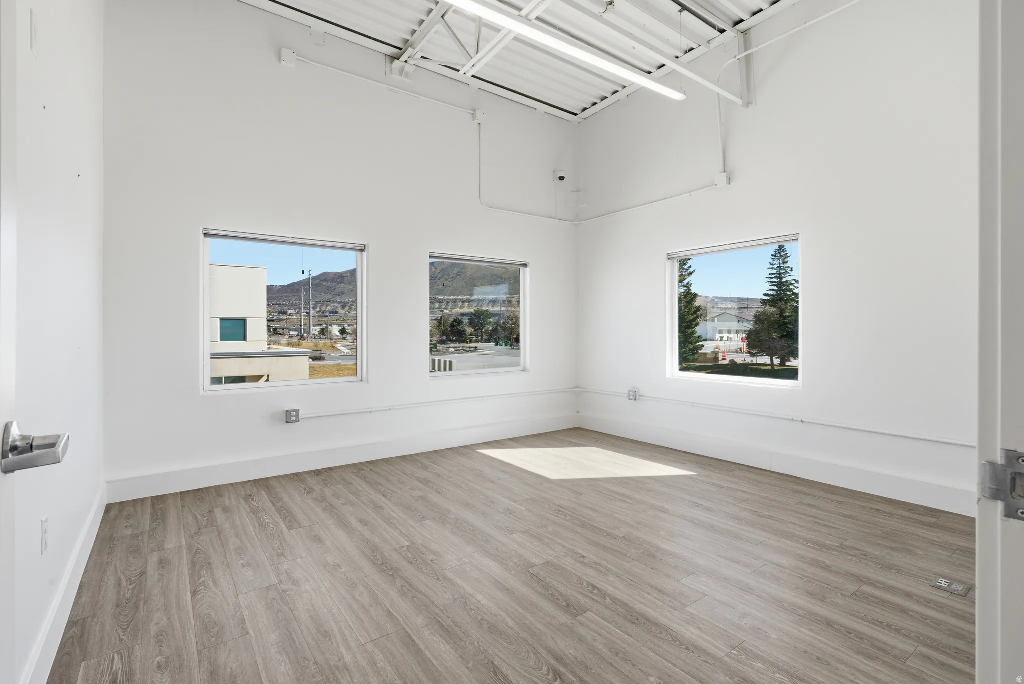 Spare room with light wood-style floors, a high ceiling, and healthy amount of natural light