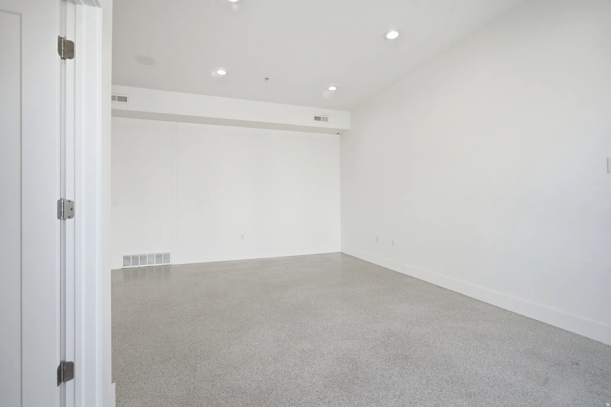 Empty room featuring speckle patterned floor and recessed lighting