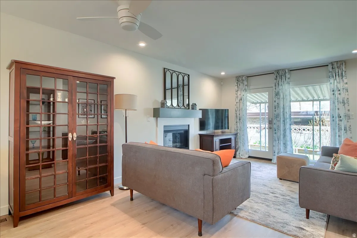 Living room w/ recessed lighting, a ceiling fan, a glass-covered fireplace, and French doors